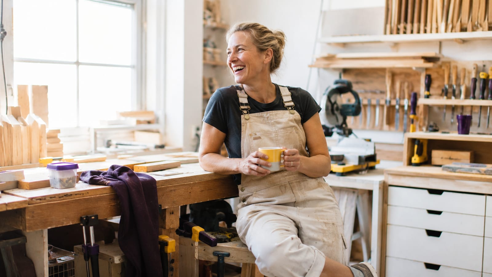Tradesperson with a coffee in a bright workshop